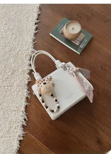 Close-up of white pebble leather handbag with woven handle and silk scarf detail