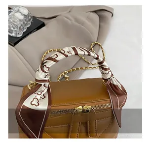 Detail of quilted brown PU leather mini bag with silk scarf handle and gold chain strap