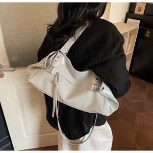 Close-up of a large ivory patent leather tote bag with stylish fringe zipper detail