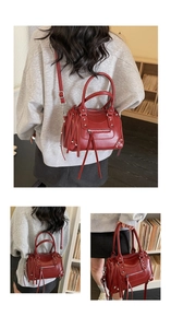 Detail of burgundy pillow bag featuring silver studs, long tassels, and shoulder strap