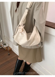 Detail of a minimalist off-white oversized crescent shoulder bag with a cute dog pendant