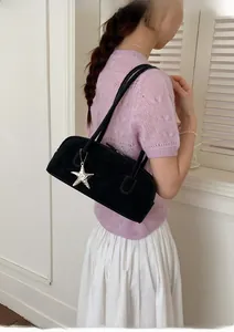 Detail of black suede rectangular shoulder bag with silver star charm and slim straps