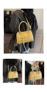 Detail view of yellow moto boston bag with studs, fringe tassels and adjustable shoulder strap