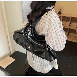 Detailed side view of a large black glossy hobo bag with long tassels and soft leather