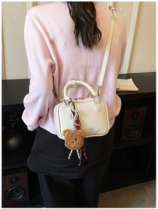 Détail d'un petit sac blanc crème avec un ours en peluche et un ruban décoratif élégant