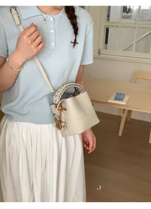 Chic cream leather bucket bag with braided handle shown on model in a modern interior