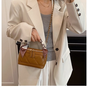 Detail of a brown quilted leather crossbody bag with scarf-wrapped handle and gold hardware