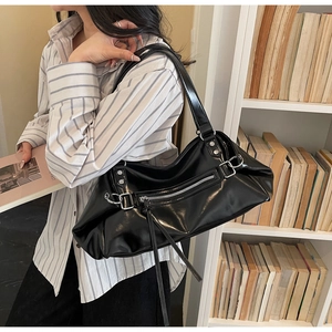 Detail of black glossy tote bag with silver hardware and stylish long tassels