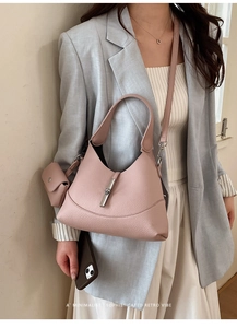 Close-up of pink lychee leather shoulder bag with silver piston clasp and mini pouch accessory