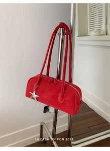 Detail view of bright red leather bowling bag with silver star charm and dual top handles