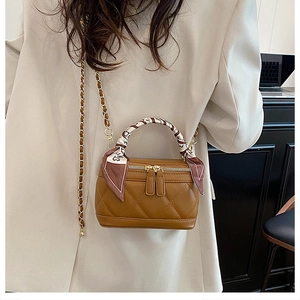 Close-up of caramel quilted mini crossbody bag with gold chain and silk scarf handle