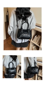 Detail of black leather Boston bag featuring punk rivets and stylish tassel zipper pulls