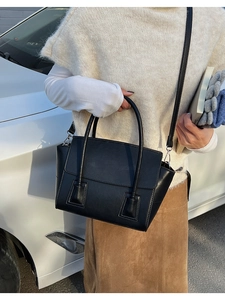 Detail of black matte trapezoid bag featuring stitching and tubular top handles