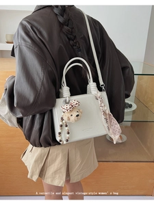Detail of white PU leather tote bag featuring rope handles and plush bear pendant