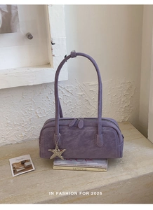 Detail view of mauve suede pillow bag featuring silver starfish charm and dual zippers