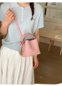 Detail of pink leather bucket bag showing woven handle and side button decoration
