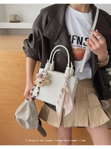 White lychee leather handbag styled with a plush bear charm and silk scarf handle detail