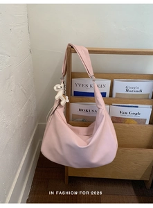 Detailed view of pink leather Hobo shoulder bag with a white horse charm on a wooden rack