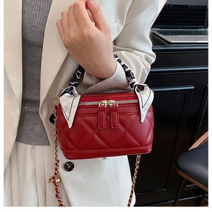 Detail of red quilted mini handbag with silk scarf handle and metal chain strap