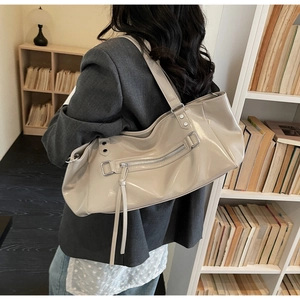 Close-up of cream tote bag with shiny faux leather texture and long tassel detail