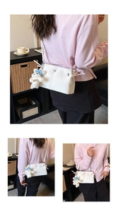 Detail of white leather shoulder bag with vertical stitching and cute bear charm