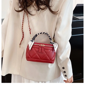 Detail of red quilted leather mini handbag with silk scarf and gold chain strap