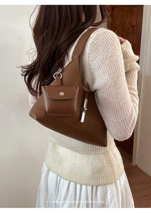 Detail of a brown lychee-grain leather dumpling bag with asymmetric triangular design