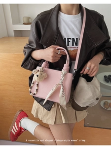 Pink leather handbag with woven handle, floral scarf detail, and cute bear pendant charm