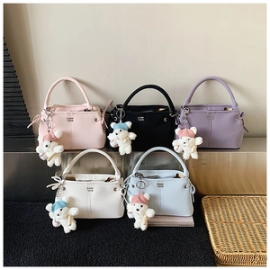 Detailed close-up of colorful leather handbags featuring cute bear charms and side bows