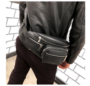 Detail of adjustable black leather chest bag with silver zippers on a street style model