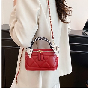 Detail of red quilted leather handbag with gold chain strap and silk scarf handle wrap