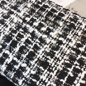 Close-up of black and white tweed fabric with silver metallic threads for a stylish handbag