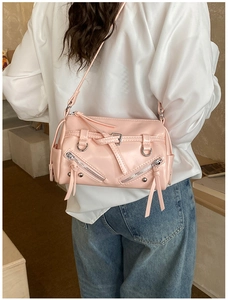 Detail of pink faux leather motorcycle bag with silver zippers shown on a model