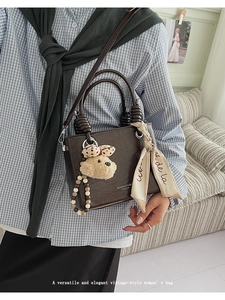 Detail of dark brown vintage handbag with silk scarf handle and cute plush bear charm