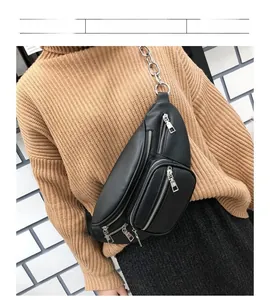 Detail of black leather chest bag featuring silver zippers and metallic chain strap
