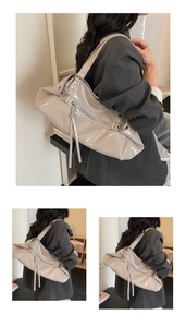 Detail view of glossy beige PU leather shoulder bag featuring long fringe and metal rings