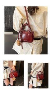 Détail du sac carré en cuir ciré bordeaux avec texte tendance et breloque ours
