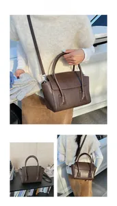 Detail view of a vintage dark brown matte handbag with top handles and shoulder strap
