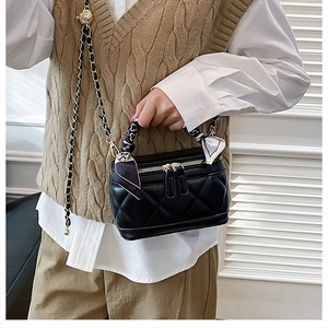 Detail of black quilted box handbag with gold chain strap and decorative silk scarf
