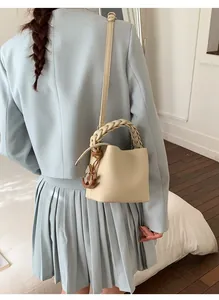 Detail of beige drawstring bucket bag with textured leather and woven handle
