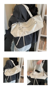 Detail of white glossy shoulder bag with silver zippers and long fringe tassels