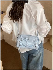 Detailed view of light blue glossy faux leather crossbody bag with punk style metal rivets