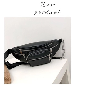 Detail of black leather waist bag with silver zippers and chunky metal chain accessory