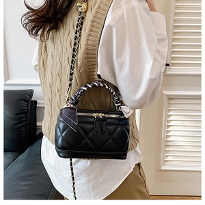 Detail of black quilted mini bag with silk scarf handle and gold chain strap