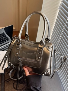Metallic gunmetal Boston bag with rivets and tassel, shown in a lifestyle office setting