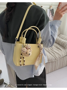 Detail of yellow pebbled leather bag with plush bear charm and silk scarf handle wrap