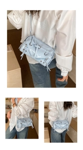 Detailed close-up of light blue moto-style bag with silver studs and polished zippers