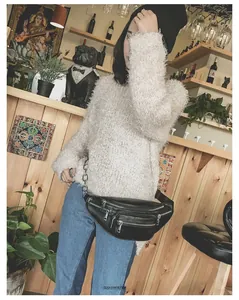 Détail d'un sac banane noir en similicuir avec chaîne métallique et fermetures éclair