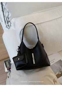 Detail of black litchi grain underarm bag with silver lock and mini pouch on sofa