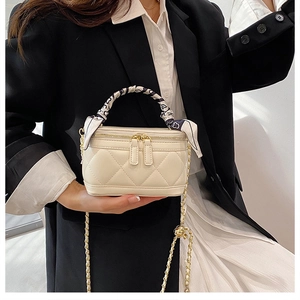 Close-up of beige quilted mini handbag with silk scarf handle and gold chain strap